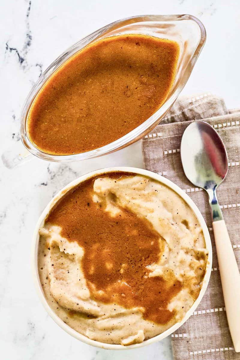 Copycat KFC gravy in a gravy boat and over mashed potatoes.