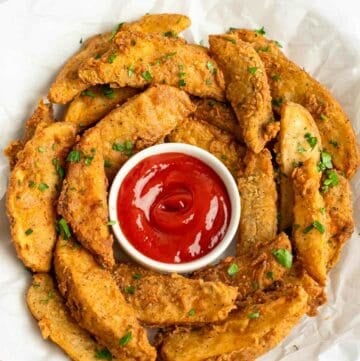 Copycat KFC potato wedges and ketchup in a serving bowl lined with parchment.