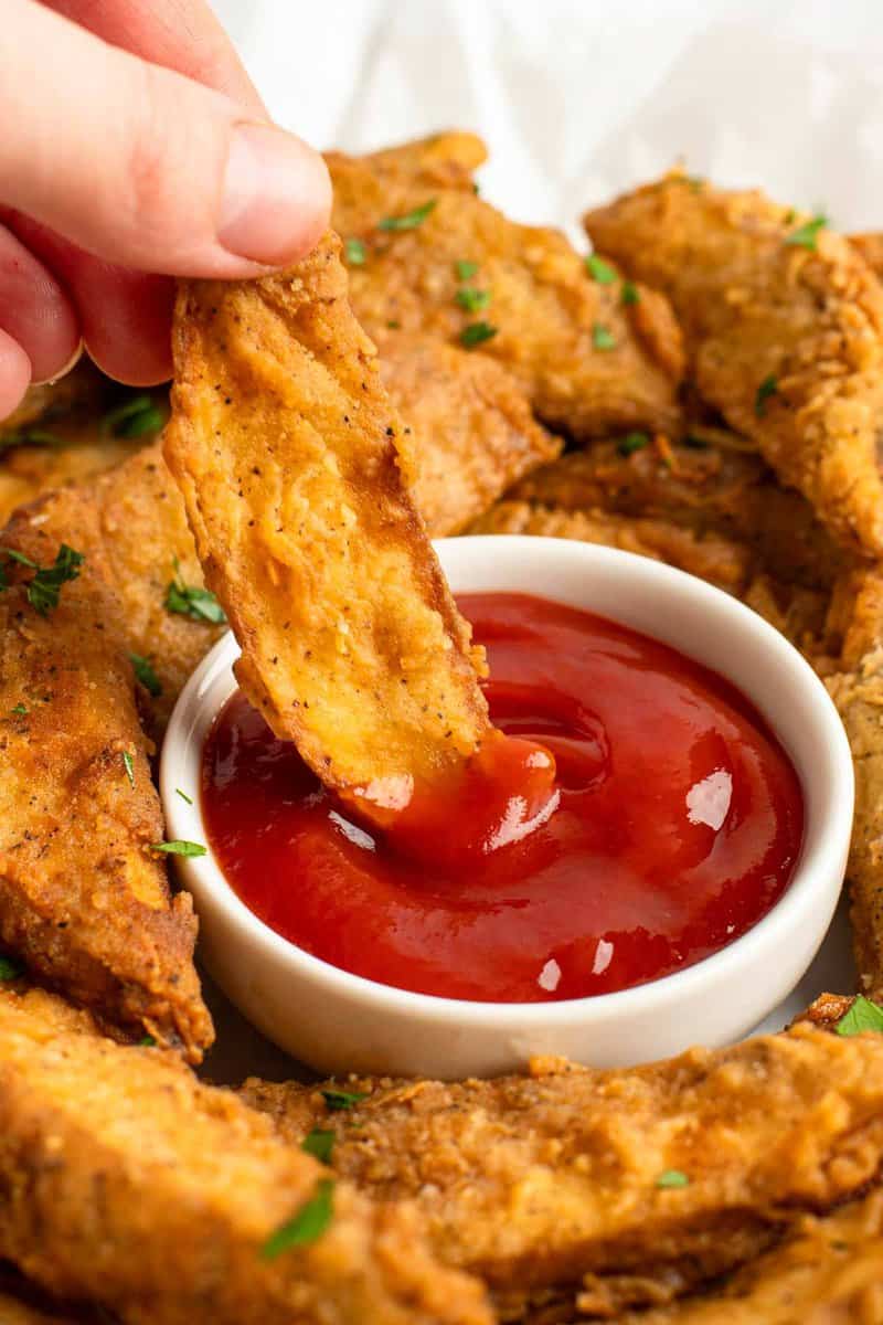 Dipping a copycat KFC potato wedge in ketchup.
