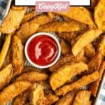 Homemade KFC potato wedges and ketchup on a baking sheet.