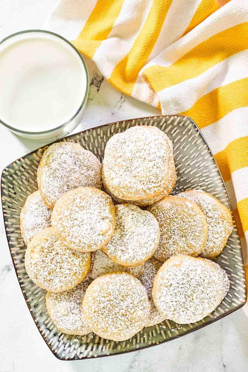 Copycat Panera lemon drop cookies, glass of milk, and kitchen towel.