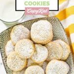 Homemade Panera lemon drop cookies on a plate and a glass of milk next to it.