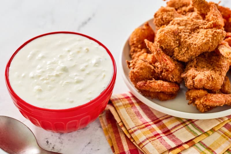 A bowl of copycat Red Lobster pina colada coconut shrimp sauce and a plate of coconut shrimp.