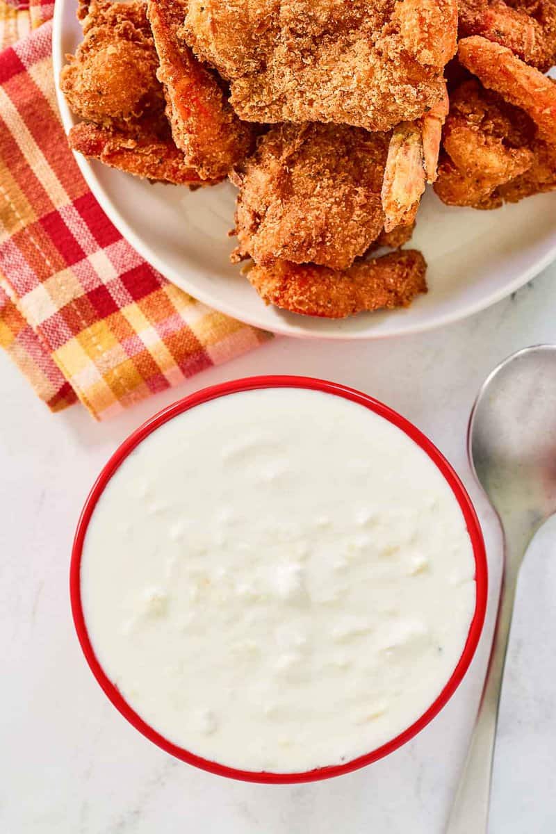 A bowl of copycat Red Lobster pina colada coconut shrimp sauce next to coconut shrimp.