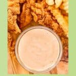 A bowl of copycat Zaxby's zax sauce next to chicken fingers and fries.
