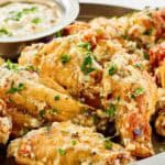 Copycat Buffalo Wild Wings garlic parmesan wings and sauce on a plate.