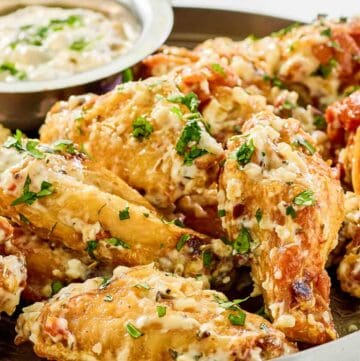 Copycat Buffalo Wild Wings garlic parmesan wings and sauce on a plate.