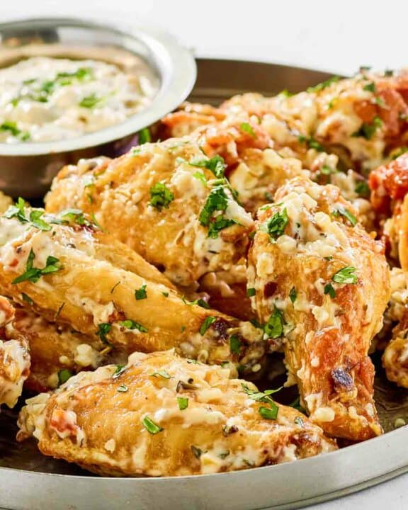 Copycat Buffalo Wild Wings garlic parmesan wings and sauce on a plate.