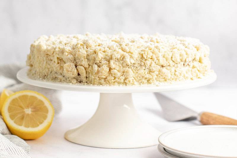 Copycat olive garden lemon cream cake on a cake stand and a lemon beside it.