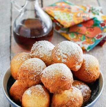 Copycat Denny's pancake puppies in a bowl and a bottle of syrup.