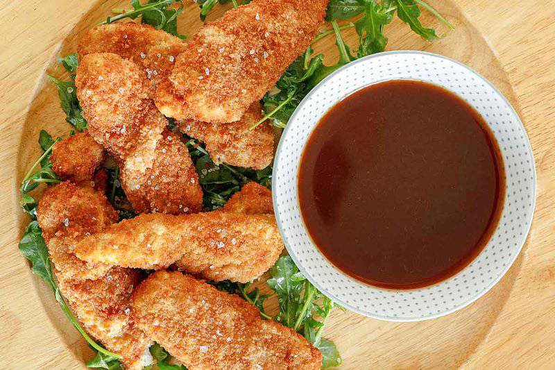 Copycat TGI Friday's jack daniels dipping sauce and chicken fingers on a plate.