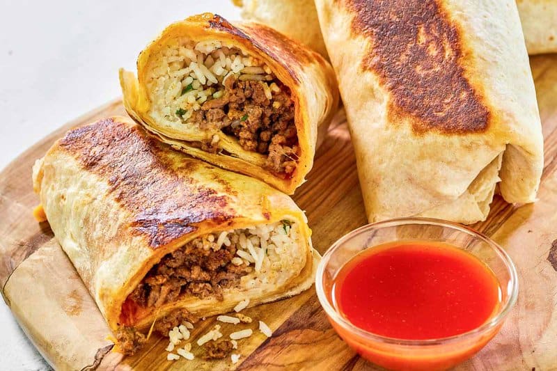 Copycat Taco Bell quesarito and taco sauce on a wood board.