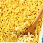 Homemade Boston Market macaroni and cheese and wooden spoon in a baking dish.