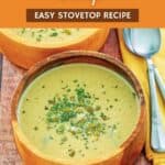 A bowl of acorn squash soup and spoons next to it.