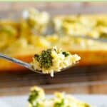 Broccoli rice casserole with cheese on a fork.