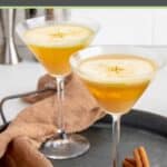 Caramel apple martini, cinnamon sticks, and cloth napkin on a serving tray.