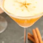 A caramel apple martini and two cinnamon sticks.