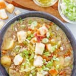 A bowl of cheeseburger soup, bacon bits, relish, and green onions.