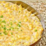 Cheesy creamed corn in a skillet on top of a braided mat.