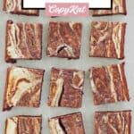 A dozen cream cheese brownies on parchment paper.