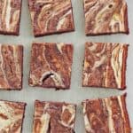 Chocolate marbled cream cheese brownies on parchment paper.