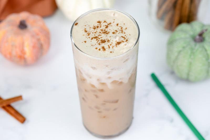 Copycat starbucks iced pumpkin cream chai latte and two small pumpkins.