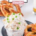 Cold beer cheese dip on a plate and soft pretzels around it.