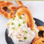 Cold beer cheese dip and a piece of a soft pretzel in it.