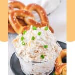 Creamy beer cheese dip and a soft pretzel on a plate.