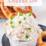 Cold beer cheese dip in a glass bowl and soft pretzels by it.