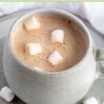 Homemade hot chocolate and mini marshmallows scattered around it.