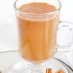 Homemade hot buttered rum in a mug and two cinnamon sticks beside it.