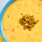 A bowl of homemade pappasito's queso dip garnished with chopped green chilies.
