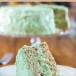 Pistachio cake slice and the cake behind it.