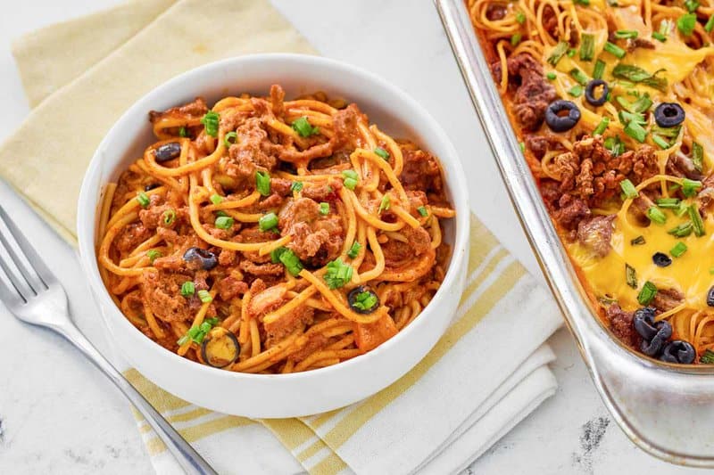 A bowl of taco spaghetti next to the casserole.