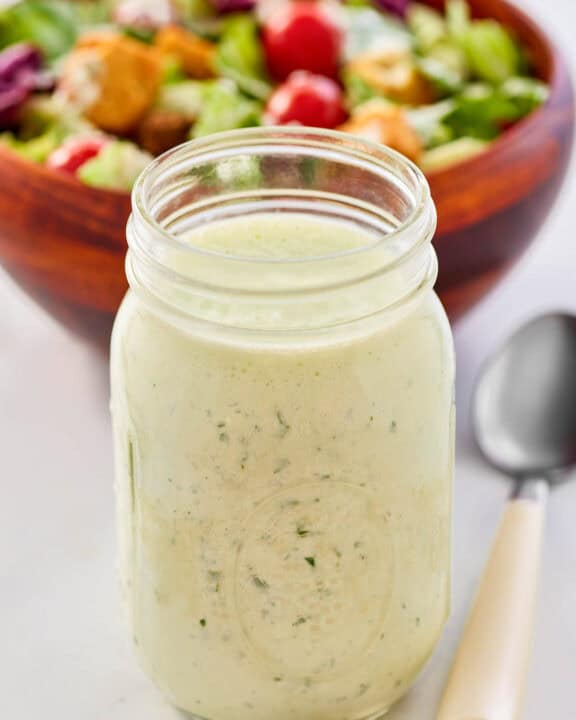 Homemade buttermilk ranch dressing, a salad, and a spoon.