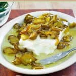 Candied jalapeno peppers over cream cheese on a platter.