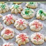 Homemade cream cheese spritz cookies with sprinkles scattered on parchment paper.