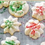 A few homemade cream cheese spritz cookies on parchment paper.