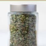 Homemade fines herbes spice blend in a small glass jar.