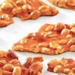 Microwave peanut brittle candy pieces on parchment paper.