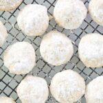 Several homemade pecan sandies on a wire rack.