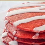 Homemade red velvet pancakes drizzled with cream cheese glaze.