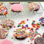 White chocolate covered oreo cookies on a wire and and scattered on parchment paper.