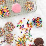 White chocolate covered oreos decorated with sprinkles and sanding sugar.