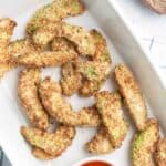Air fryer avocado fries and dipping sauce on a plate.