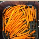 Carrot sticks in an air fryer basket.