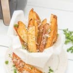 Air fryer potato wedges garnished with parmesan cheese and parsley.