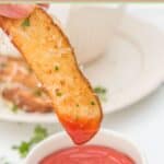An air fried potato wedge dipped in ketchup.