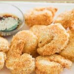 Air fryer shrimp tempura and a small cup of dipping sauce.